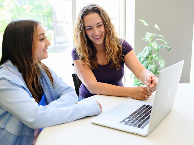 Educator and student working together on a laptop